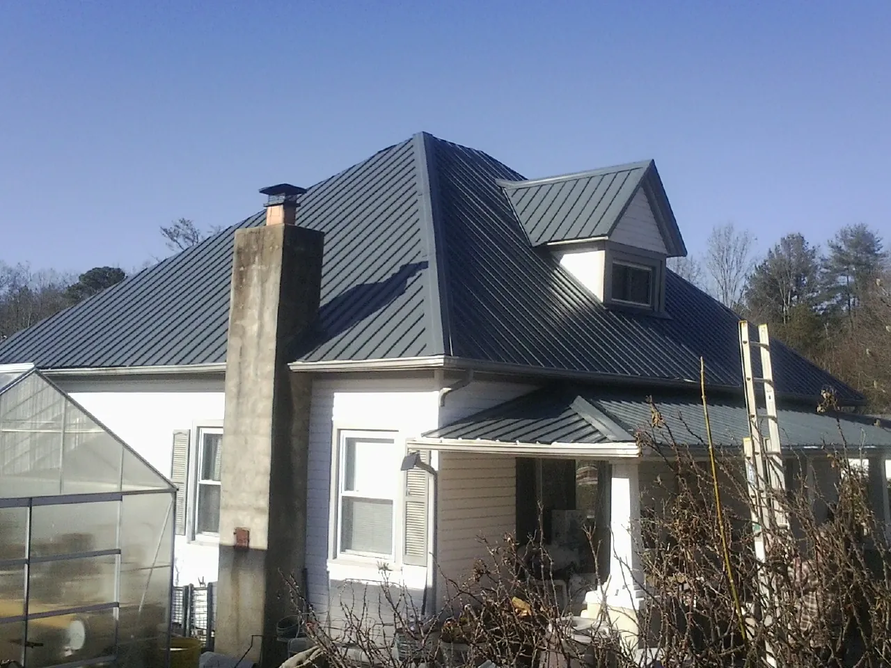 Dark blue standing seam metal roof on a white farmhouse with dormer — Slate & Tile Roof Repair by Roofing Brothers in Mormon Lake