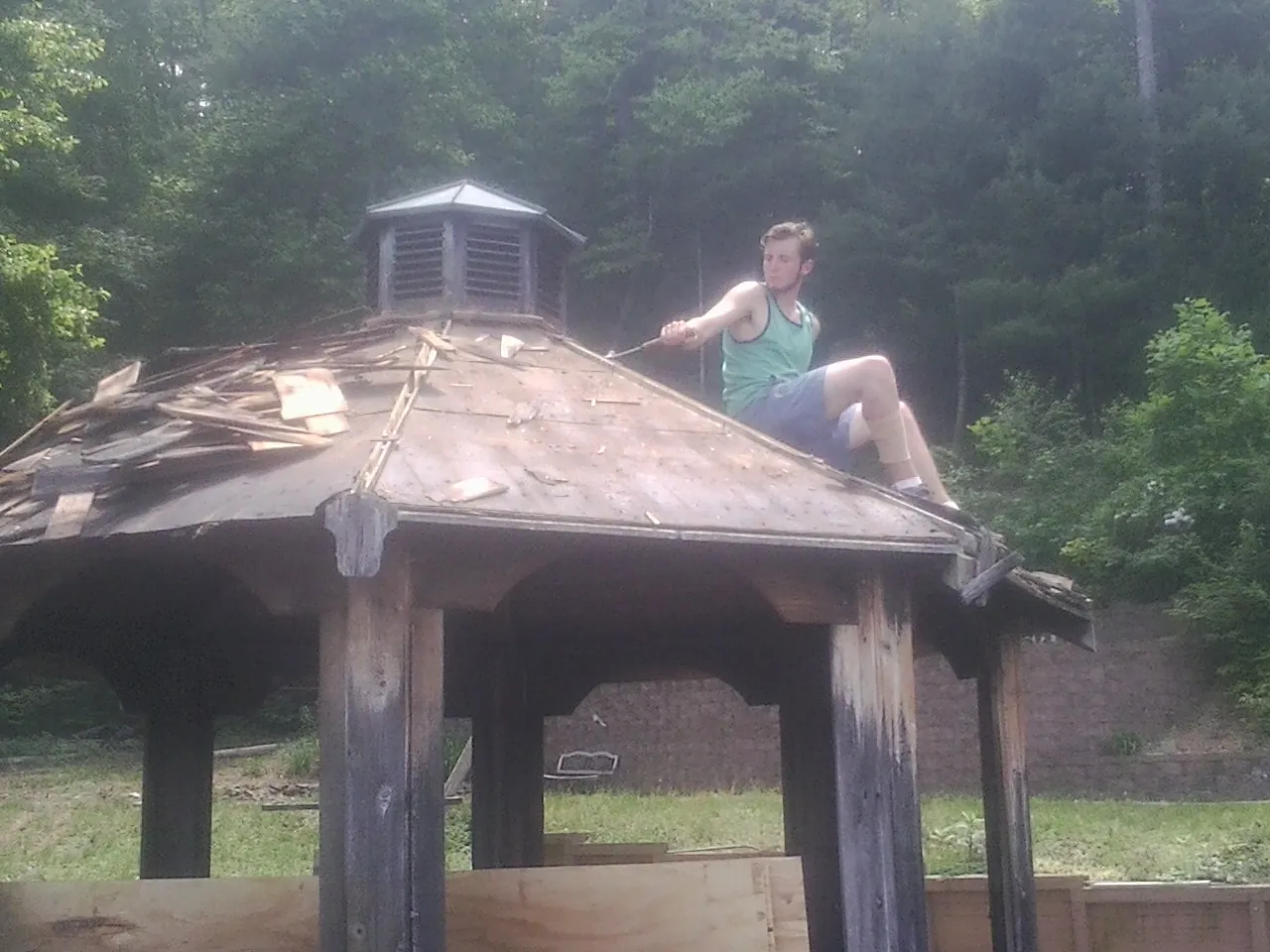 Tearing the old roof off a wooden gazebo before new shakes in Mormon Lake