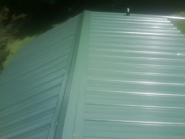 New green metal panels meeting at the ridge of a roof — Flat Roof Repair work by our crew in Mormon Lake