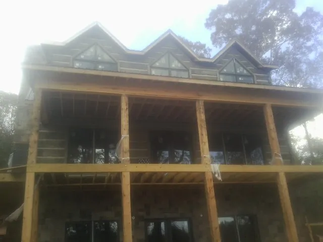 Dormers and porch framing on a large log home under construction — Roof Coating work by our crew in Mormon Lake