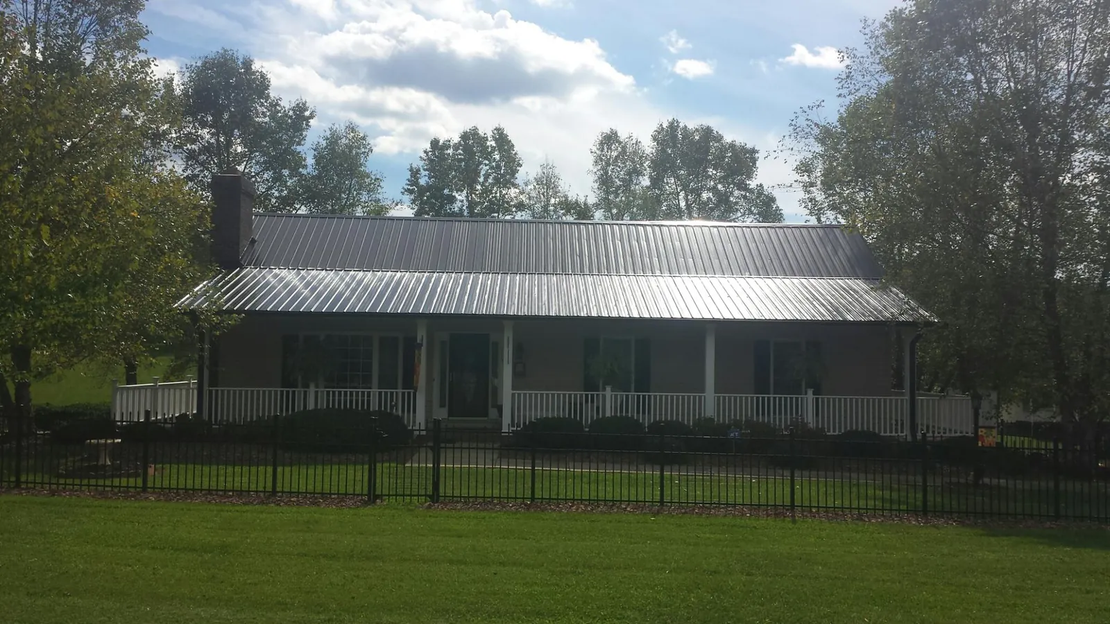 Gray metal roof on a brick ranch with a full width front porch — Gutter Guard Installation work by our crew in Mormon Lake