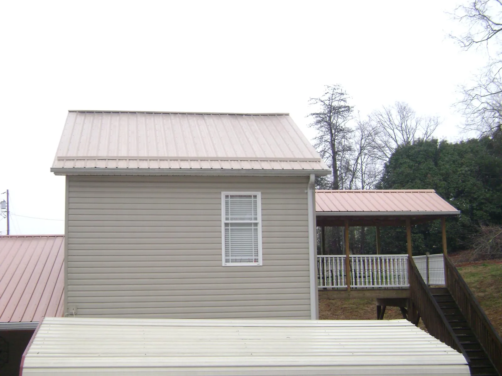 Tan metal roofs on a two story addition and attached porch, from a Roof Replacement job in Mormon Lake