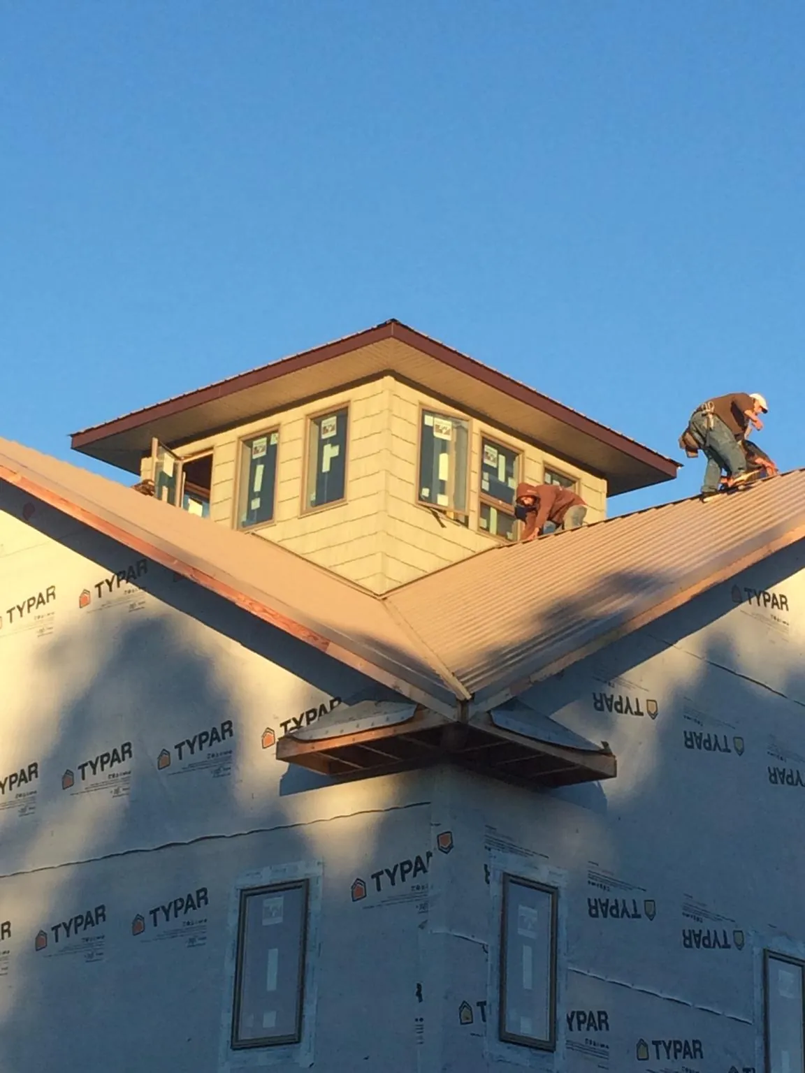 Roofers working around a rooftop cupola on a new metal roof at sunset — Roof Waterproofing in Mormon Lake by Roofing Brothers